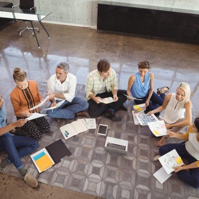 Business people working while sitting on floor in creative office